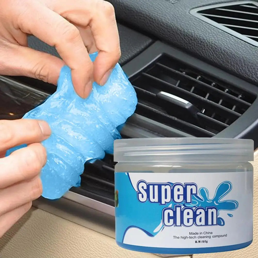 Hand pulling blue cleaning gel away from a car air vent next to the product jar
