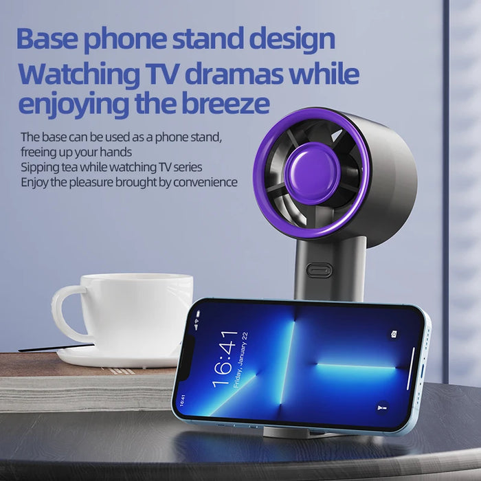 Mini handheld fan base used as a phone stand next to a coffee cup on a table