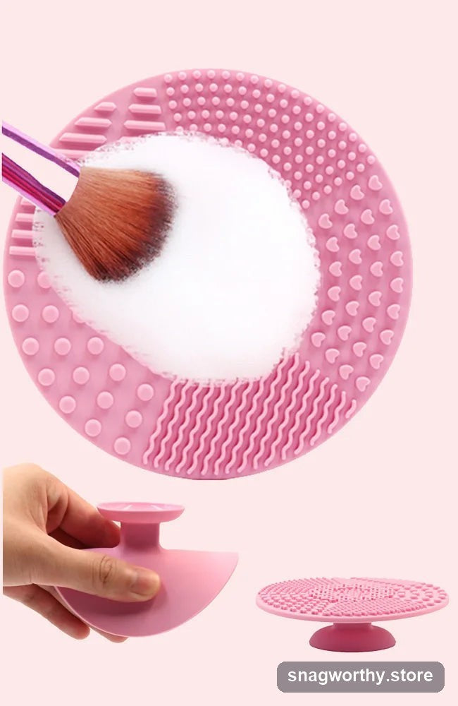 Pink silicone makeup brush cleaning mat with a brush being cleaned in suds, and held in hand | Snagworthy.store