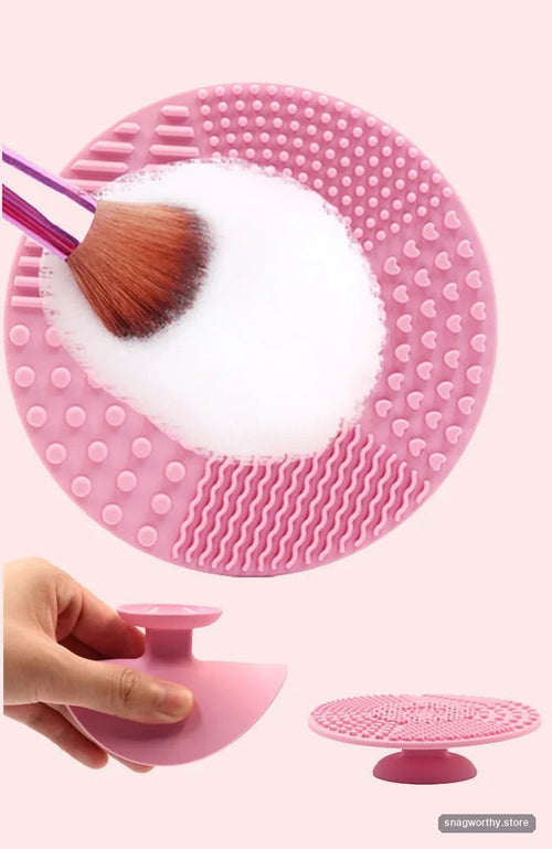 Pink silicone makeup brush cleaning mat with a brush being cleaned in suds, and held in hand | Snagworthy.store