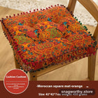 PlushSit tufted floor cushion in orange on a wooden chair, close-up | Snagworthy.store